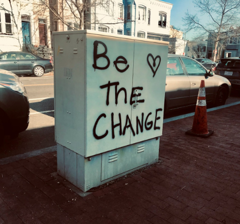 graphitti in black spraypaint on an electric box reads"Be the change"
